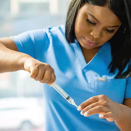 Vein technician prepping a needle for sclerotherapy treatment